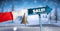 Sale text and Santa holding bell with Wooden signpost in Christmas Winter landscape Royalty Free Stock Photo