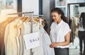 SALE, what a beautiful word. a woman looking at dresses on a rail with a sign that reads sale. Royalty Free Stock Photo