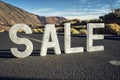 Sale - white letters on the asphalt road near Teide volcano, blue sky, sunny light.