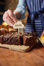 Sales Assistant In Bakery Putting Homemade Label Into Freshly Baked Baked Chocolate Brownies Royalty Free Stock Photo