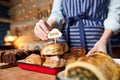 Sales Assistant In Bakery Putting Homemade Label Into Stack Of Freshly Baked Baked Cinnamon Buns Royalty Free Stock Photo