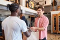 Sales Assistant Handing Purchases To Male Customer In Fashion Store Royalty Free Stock Photo