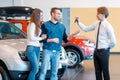 Sales consultant gives keys from new car to young Royalty Free Stock Photo