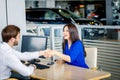 Sales manager and female customer shaking hands congratulating each other at the dealership showroom. Royalty Free Stock Photo