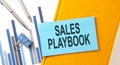 SALES PLAYBOOK text on sticker on the yellow notebook with chart and pen