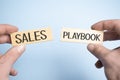 sales playbook on wooden block with in businessman hands