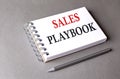 SALES PLAYBOOK word on notebook on grey background