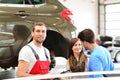 after-sales service in the garage - mechanics and young couple talk about repairing a vehicle