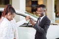 Sales situation in car dealership, young african couple gets the key for new car Royalty Free Stock Photo