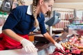 Sales woman in butcher shop putting different kinds of meat in display Royalty Free Stock Photo