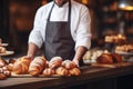 Salesman in bakery behind counter with bakery products