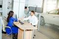 Sales manager and female customer shaking hands congratulating each other at the dealership showroom. Royalty Free Stock Photo