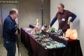 Sales table covered in gems, crystals, and minerals, with a seller and customer