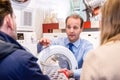 Salesman Explaining Product To Couple In Hypermarket