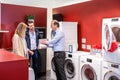 Salesman Explaining To Couple In Washing Machine Department Royalty Free Stock Photo