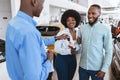 Salesman giving car key to young black couple at auto dealership. Vehicle local distribution concept Royalty Free Stock Photo
