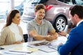 Salesman giving the key of the new car to a young couple at the dealership showroom Royalty Free Stock Photo
