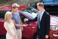 Salesman giving key to couple by car