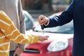 Salesman giving key to customers in auto dealership, closeup. Buying new car Royalty Free Stock Photo