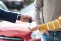 Salesman giving key to customers in auto dealership, closeup. Buying new car Royalty Free Stock Photo