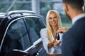 Salesman giving keys from new car to female customer Royalty Free Stock Photo