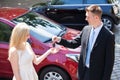 Salesman Handing Key To Woman By New Car