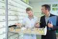 Salesman looking in open drawer with pharmacist