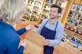 Salesman putting wine bottle in paperbag for customer