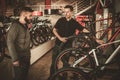 Salesman showing a new bicycle to interested customer in bike shop. Royalty Free Stock Photo