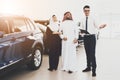 Salesman shows new car to an Arab couple in store.