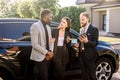 Salesman with tablet and clients, business couple, Caucasian woman and African man, standing near new car outdoors