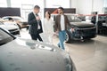 Salesman and woman looking for car in car showroom choosing perfect automobile