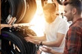 A salesperson at a bicycle store helps a young buyer choose tires for a bicycle.