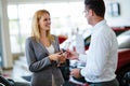 Professional salesperson during work with customer at car dealership. Giving keys to new car owner. Royalty Free Stock Photo