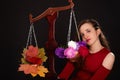 A saleswoman of beautiful autumn mood weighs flowers and colorful autumn maple leaves on a scales. Funny concept