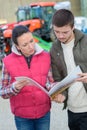 Saleswoman convincing young famrer to buy new agricultural machinery Royalty Free Stock Photo