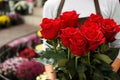 Saleswoman holding bouquet of beautiful roses in shop