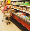 Saleswoman lays out dairy products on a refrigerated display rack