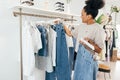 Saleswoman standing in clothing store, arranging clothes on a rail