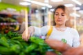 Spanish woman employee in vegetable store with green peppers