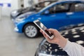 Saleswoman using mobile smart phone at dealer showroom. Modern working process Royalty Free Stock Photo