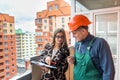 Saleswoman writing in notepad and builder standing near