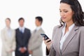 Saleswoman writing text message with colleagues behind her