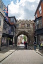 The medieval North Gate, known as the High Street Gate, to the Cathedral Close. Tourists walk along High Street, leading to