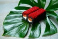 Salmon Black rice sushi roll with cattle fish inks on tropical leaf. Roll with cream cheese and red flying fish roe Tobiko