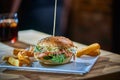 Salmon burger with french fries on a pub background