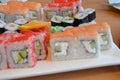 Salmon and caviar rolls served on a plate. sushi or rolls are held with chopsticks. with soy sauce, ginger and wasabi