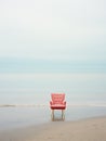 Salmon-colored armchair on sandy beach at the seaside. Minimalist retro style image, pastel tones. Generative AI