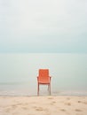 Salmon-colored empty chair on sandy beach at the seaside. Minimalist retro style image, pastel tones. Generative AI