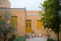 Salmon colored house facade and yellow doors and windows with an olive and lemon tree in the front yard on Aegina island, Greece